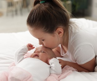Photo of Cute girl and her little sister on bed at home