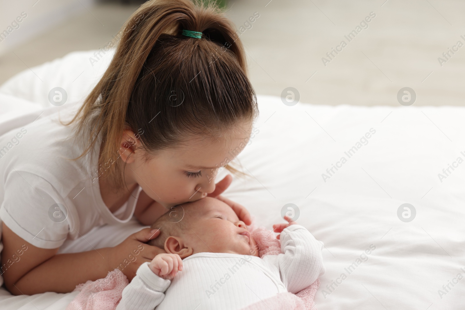 Cute girl and her little sister on bed at home, space for text Photo of Cute girl and her little sister on bed at home, space for text