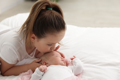 Photo of Cute girl and her little sister on bed at home, space for text