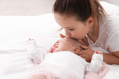Photo of Cute girl and her little sister on bed at home