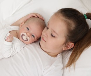 Photo of Cute girl and her little sister on bed at home