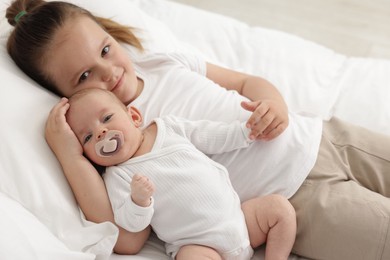 Photo of Cute girl and her little sister on bed at home