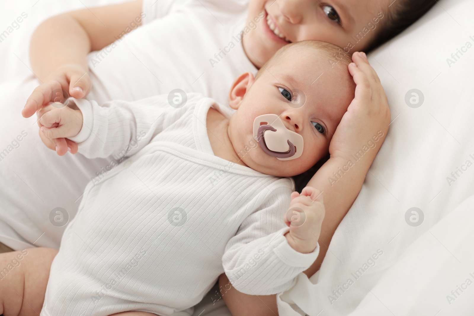 Cute girl and her little sister on bed at home, selective focus Photo of Cute girl and her little sister on bed at home, selective focus