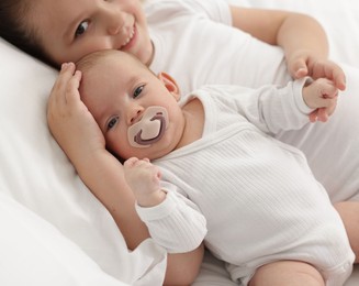 Photo of Cute girl and her little sister on bed at home, selective focus