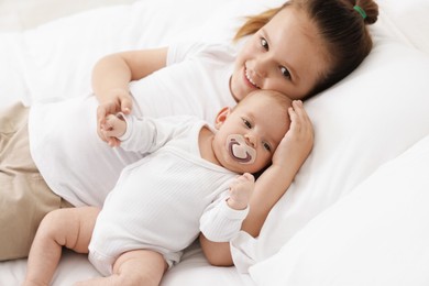Photo of Cute girl and her little sister on bed at home