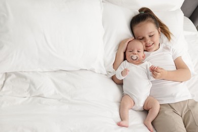 Photo of Cute girl and her little sister on bed at home, space for text