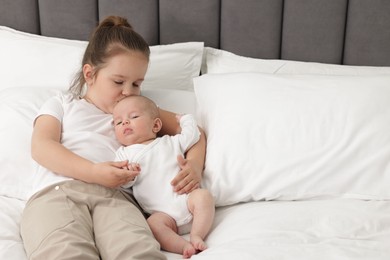 Photo of Cute girl and her little sister on bed at home, space for text