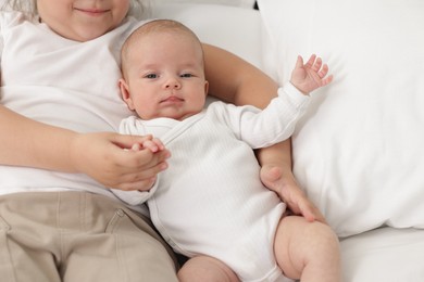 Photo of Cute girl and her little sister on bed at home, closeup