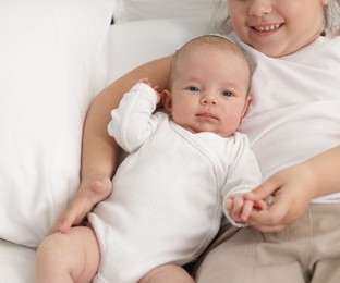 Photo of Cute girl and her little sister on bed at home, closeup