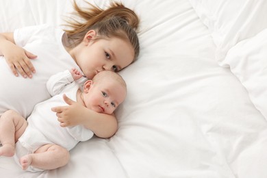 Photo of Cute girl and her little sister on bed at home, above view. Space for text