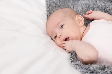 Photo of Cute little baby on bed at home, space for text