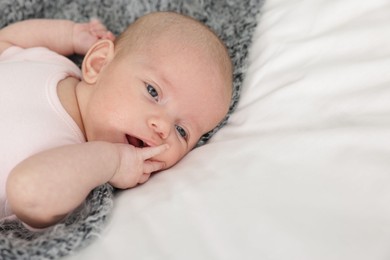 Photo of Cute little baby on bed at home, space for text