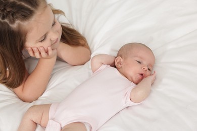 Photo of Little girl and her cute sister on bed at home, above view