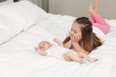 Photo of Cute girl and her little sister on bed at home, space for text