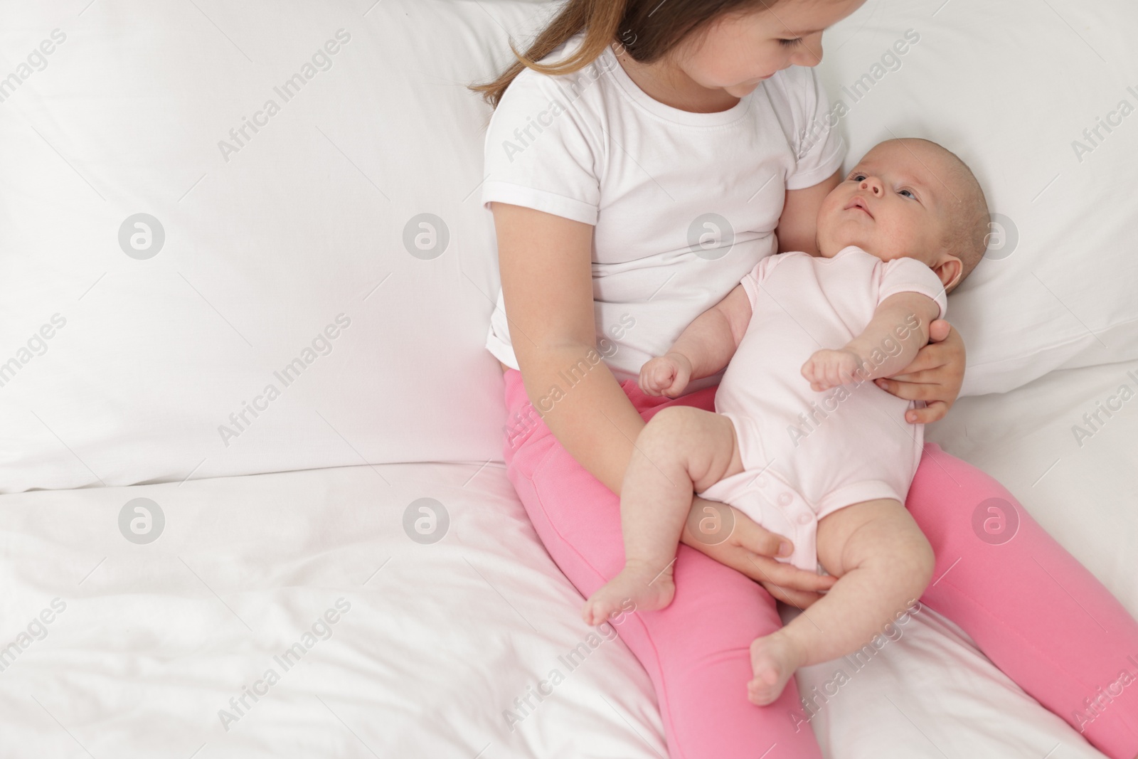 Cute girl and her little sister on bed at home, space for text Photo of Cute girl and her little sister on bed at home, space for text