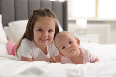 Photo of Cute girl and her little sister on bed at home