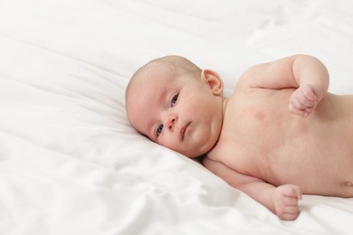 Photo of Cute little baby lying on bed at home, space for text