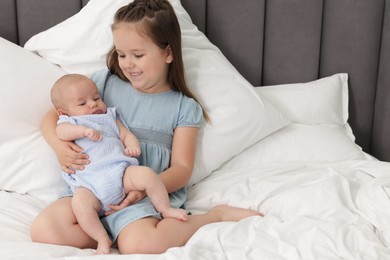 Photo of Cute girl and her little sister on bed at home, space for text