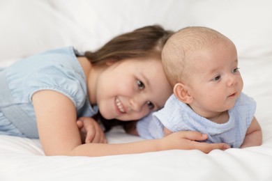 Photo of Cute girl and her little sister on bed at home