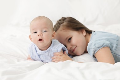 Photo of Cute girl and her little sister on bed at home