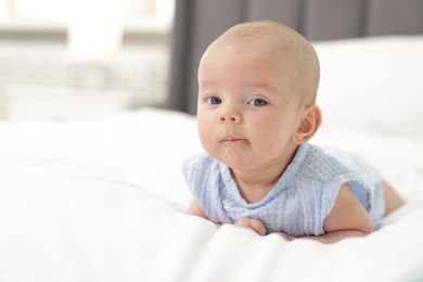 Photo of Cute little baby on bed at home, space for text