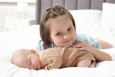 Photo of Cute girl and her little sister on bed at home