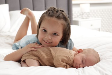 Photo of Cute girl and her little sister on bed at home
