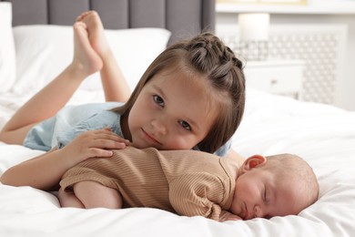 Photo of Cute girl and her little sister on bed at home