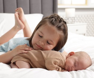 Photo of Cute girl and her little sister on bed at home
