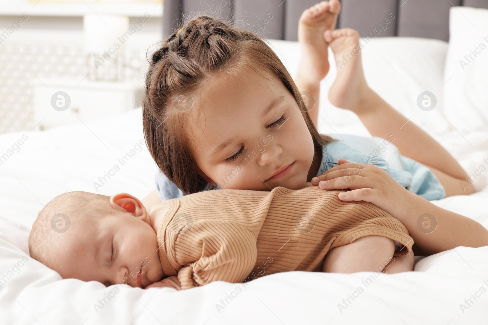 Cute girl and her little sister on bed at home Photo of Cute girl and her little sister on bed at home