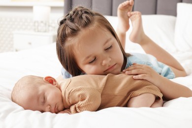 Photo of Cute girl and her little sister on bed at home