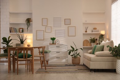 Photo of Stylish dining table with chairs and comfortable sofa in room. Interior design