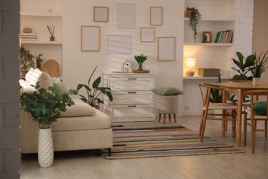 Photo of Stylish dining table with chairs and comfortable sofa in room. Interior design