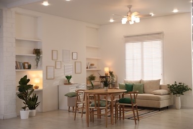 Photo of Stylish dining table with chairs and comfortable sofa in room. Interior design
