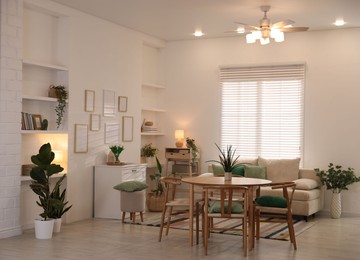 Photo of Stylish dining table with chairs and comfortable sofa in room. Interior design