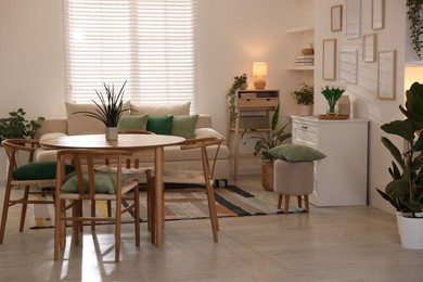 Photo of Stylish dining table with chairs and comfortable sofa in room. Interior design