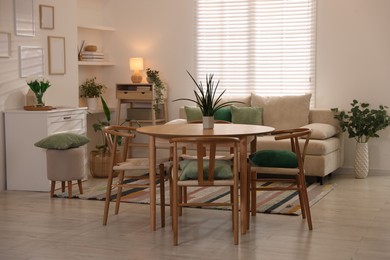 Photo of Stylish dining table with chairs and comfortable sofa in room. Interior design