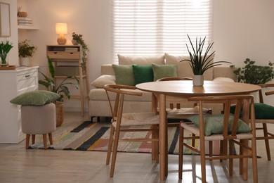 Photo of Stylish dining table with chairs and comfortable sofa in room. Interior design