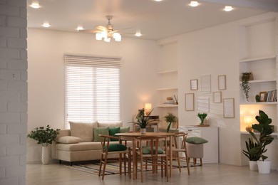Photo of Stylish dining table with chairs and comfortable sofa in room. Interior design