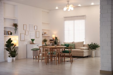 Photo of Stylish dining table with chairs and comfortable sofa in room. Interior design