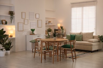 Photo of Stylish dining table with chairs and comfortable sofa in room. Interior design