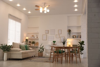 Photo of Stylish dining table with chairs and comfortable sofa in room. Interior design