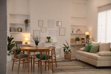 Photo of Stylish dining table with chairs and comfortable sofa in room. Interior design