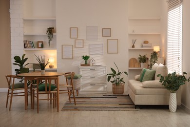Photo of Stylish dining table with chairs and comfortable sofa in room. Interior design