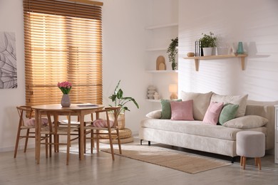 Photo of Stylish dining table with chairs and comfortable sofa in room. Interior design