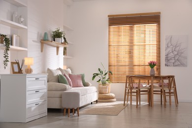 Photo of Stylish dining table with chairs and comfortable sofa in room. Interior design