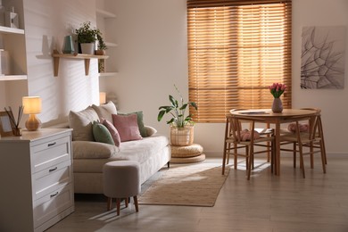Photo of Stylish dining table with chairs and comfortable sofa in room. Interior design