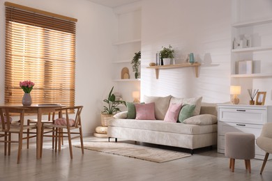 Photo of Stylish dining table with chairs and comfortable sofa in room. Interior design