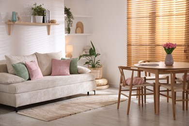 Photo of Stylish dining table with chairs and comfortable sofa in room. Interior design