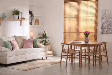 Photo of Stylish dining table with chairs and comfortable sofa in room. Interior design